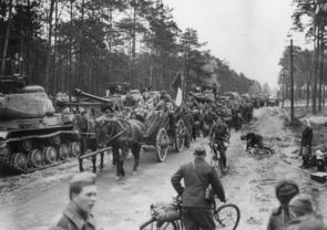 Befreite französische Zwangsarbeiter*innen zwischen sowjetischen Panzern auf einer Straße westlich von Berlin, Mai 1945